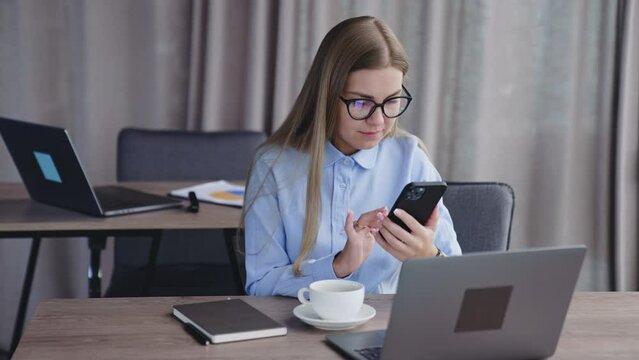 Successful young business famele manager typing on smartphone. European focused businesswoman concept.