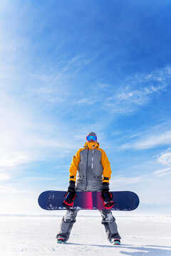 Young man holds a snowboard in his hands against the background of a winter landscape.