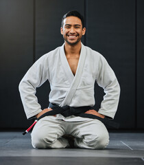 Fototapeta Mma, karate and training with a young man kneeling in a gym, health studio or dojo in his gi or uniform. Portrait of a male training, exercising and learning self defense in a workout and fight class obraz