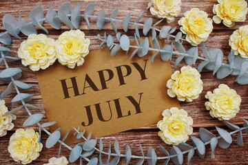 Happy July typography text on paper card decorate with flower on wooden background