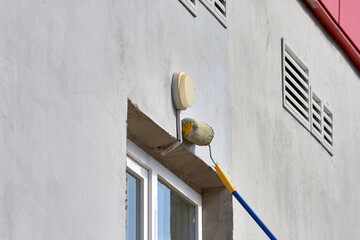 painting the street wall with a roller with gray paint