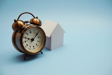 Alarm clock and house model with space copy on blue background