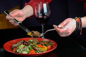 warm salad with veal in a red plate on a dark background macro photo

