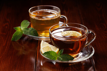 Hot green tea with mint and tea with lemon in glass cups. Selective focus. Angle view. Close-up.