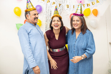 Happy Indian asian old couple celebrate birthday with daughter. elderly retired people and young doing party together.