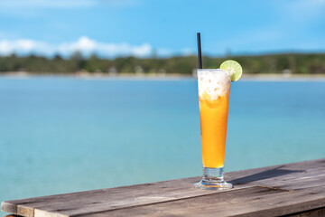 Summer Vacation Concept : Fruit cocktail glass. Welcome drink orange juice punch put on wooden table nearly the sea.