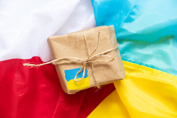 A paper box with a painted flag of Ukraine lies on the flags of Poland and Ukraine , humanitarian...