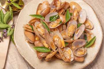 Stir fried clams with basil leaves in a white bowl
