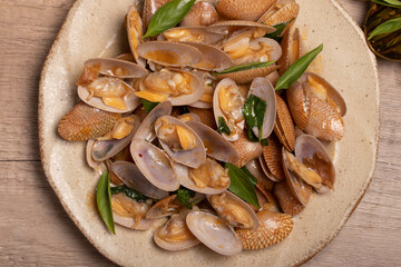 Stir fried clams with basil leaves in a white bowl