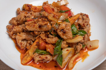 Pork stir fried in chili paste with tomatoes and onions in a white dish