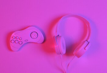 White Headphones with gamepad in pink-blue neon gradient light. Minimalism gaming concept