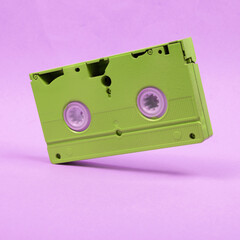 Levitating green video cassette on pink background. 3D photo. Minimalistic still life. Creative layout. Concept art