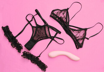Set of black lingerie and sexy toy on pink background