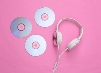 Musical layout. Headphones and cd on pink background. Top view. Flat lay