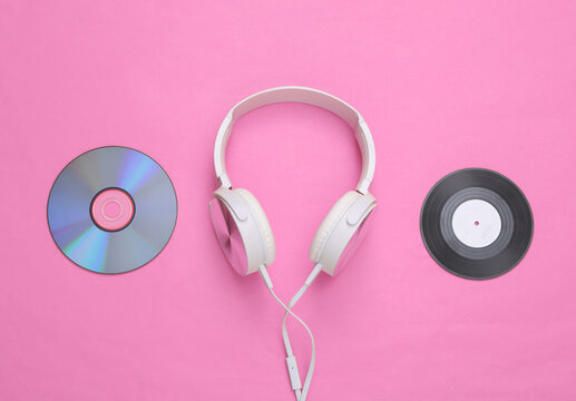 Musical layout. Headphones, vinyl record and cd on pink background. Top view. Flat lay