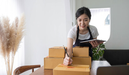 Portrait of Asian young woman SME working with a box at home the workplace.start-up small business...