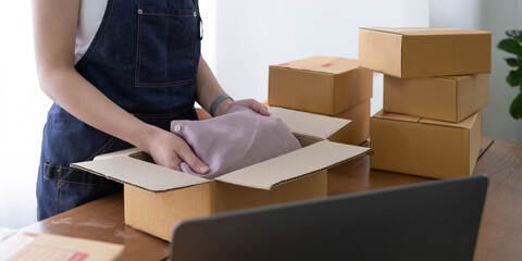 Startup small business entrepreneur SME, asian woman packing shirt in box. Portrait young Asian small business owner home office, online sell marketing delivery, SME e-commerce telemarket job concept