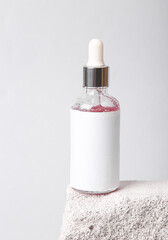 Product photo. Mockup of face serum bottle with blank label on natural porous stone. Beauty concept, facial skin care