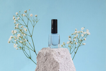 Beauty products. Nail polish bottle on stone, blue background. Product photo. Abstract natural...
