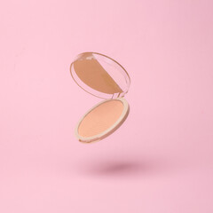Powder box flying in antigravity on pink background with shadow. Levitation object in the air. Beauty and fashion concept. Creative minimalist layout