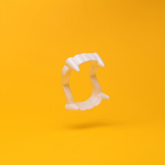 Plastic vampire jaw with fangs flying in antigravity on yellow background with shadow. Levitation...