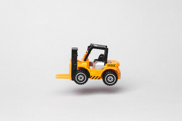 Miniature toy forklift flying in antigravity on gray background with shadow. Levitation object in the air. Logistics, transportation concept. Creative minimal layout