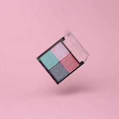 Eye shadow palette flying in antigravity on pink background with shadow. Levitation object in the air. Beauty and fashion concept. Creative minimal layout