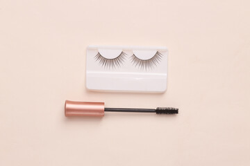 Mascara brush with false eyelashes on a beige background