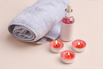 Obraz na płótnie Canvas Spa salon, beauty concept. Serum bottle with aroma candles and a towel on a beige background