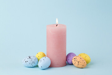Flaming candle with Easter eggs on a blue background