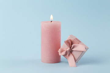 Flaming candle with a surprise box on a blue background. Pastel color trend. Romantic concept