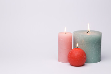 Different shapes of burning candles on a white background
