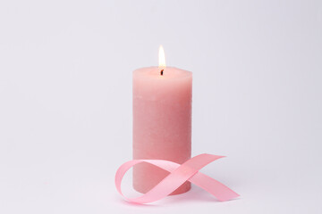 Pink ribbon for breast cancer awareness campaign with flaming candle on white background