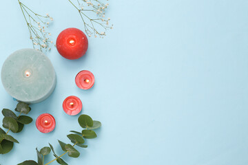 Aroma candles with sprigs of eucalyptus on blue background. Spa, aromatherapy. Copy space