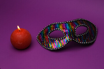 Romantic concept. Carnival mask with a flaming candle on a purple background
