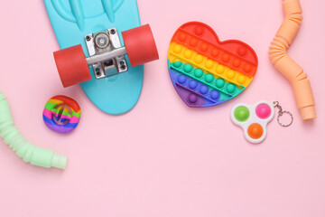Popular Sensory anti-stress toys with penny board on pink background. Copy space. Top view