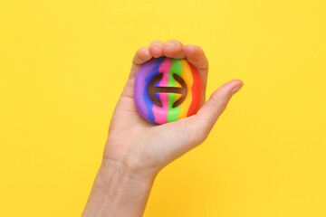 Hand squeezing antistress toy on yellow background