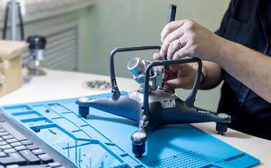 Professional repair of RC drones and radio controlled cars, robots.Broken quadrocopter lies on workshop