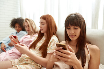 Obraz na płótnie Canvas Girl using smartphone with her blurred girlfriends