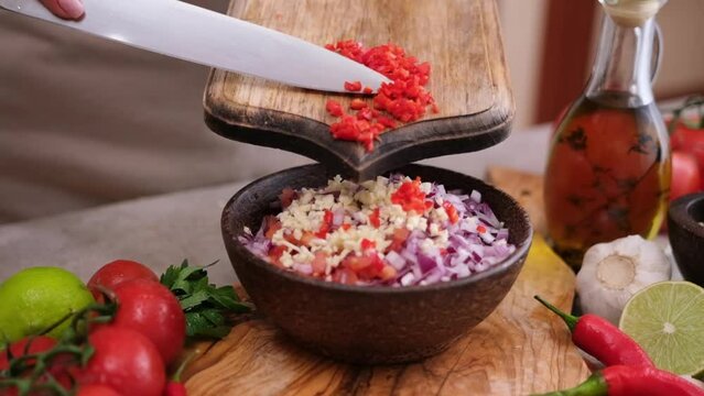 Cooking salsa dip sauce - Woman pours chopped sliced chili pepper to wooden bowl