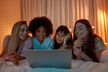 Girl friends watch laptop during girlish sleepover