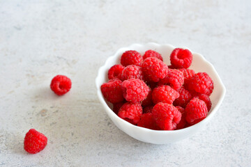 ripe red raspberries in white bowl isolated, close-up