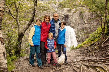 Happy european family with kids and dog, enjoying the hike to Manafossen waterfall summertime