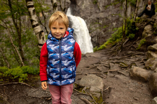 Happy european family with kids and dog, enjoying the hike to Manafossen waterfall summertime