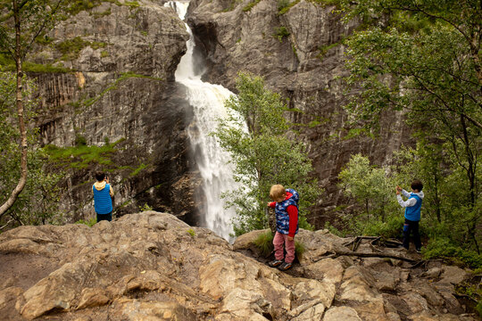 Happy european family with kids and dog, enjoying the hike to Manafossen waterfall summertime