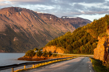 Grey road in Norvegian mountains in sunny night