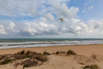 Evening view on small sand dune with green grass. Sandy beach at sea coast. Blue sky with white clouds. Sunset time