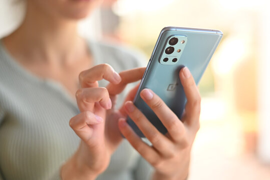 close-up woman uses modern phone Oneplus 9r flipping through news feed at home. to write a message