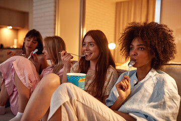 Multiracial girls eat ice cream and watch movie