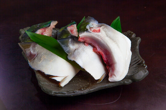 脂がのった新鮮な鰤カマの塩焼き用切り身、高級感のある黒い皿に盛り付けられた調理前の魚介素材 | Fresh Raw Yellowtail Collar (Buri Kama) Slices for Grilling on a Black Plate